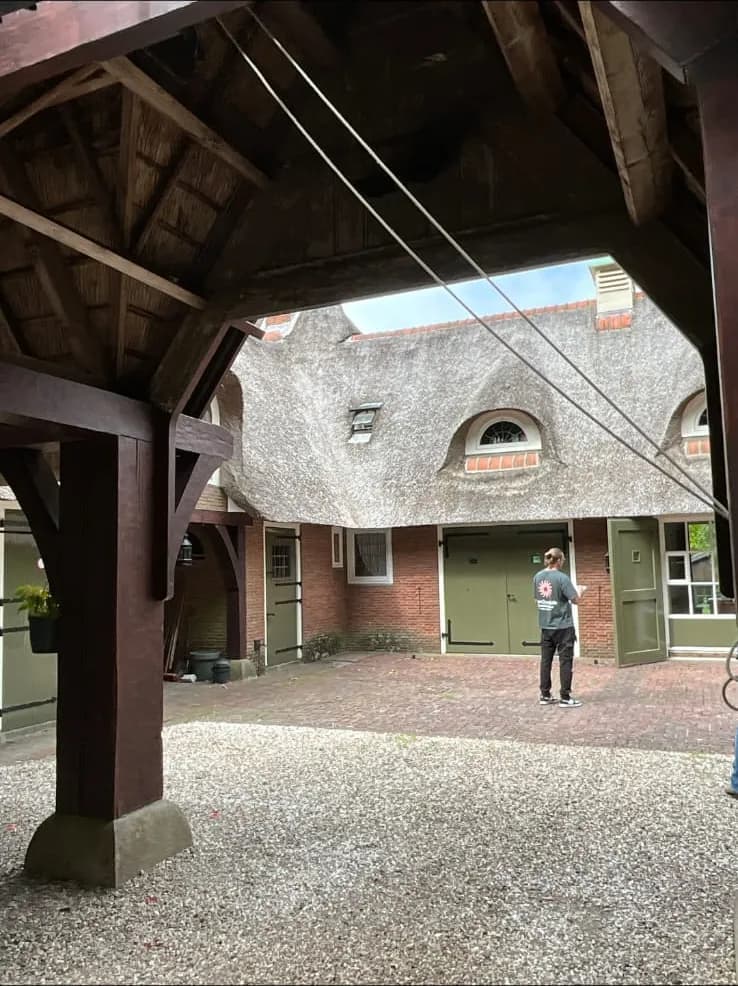 Opname van een rietgedekte woning met bijgebouwen op het erf